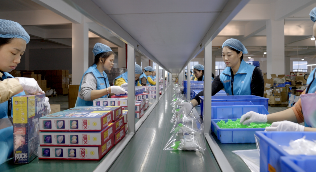K&M factory production line — workers assembling and packing educational science kits for shipment